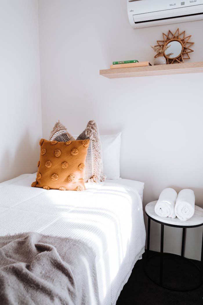A bright and cozy minimalist bedroom with textured cushions and elegant furniture.